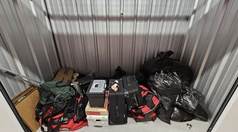 The storage unit auction listing photo: duffel bags, luggage and boxes, with the duffel bag marked