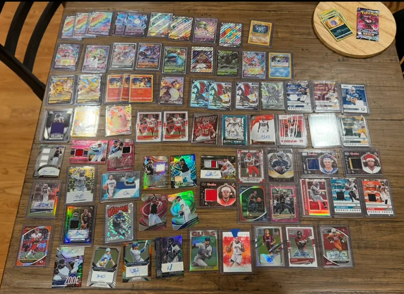Cards from the winter storage unit laid out on a table: Pokémon cards including Charizard and Pikachu, and sports autograph and patch cards
